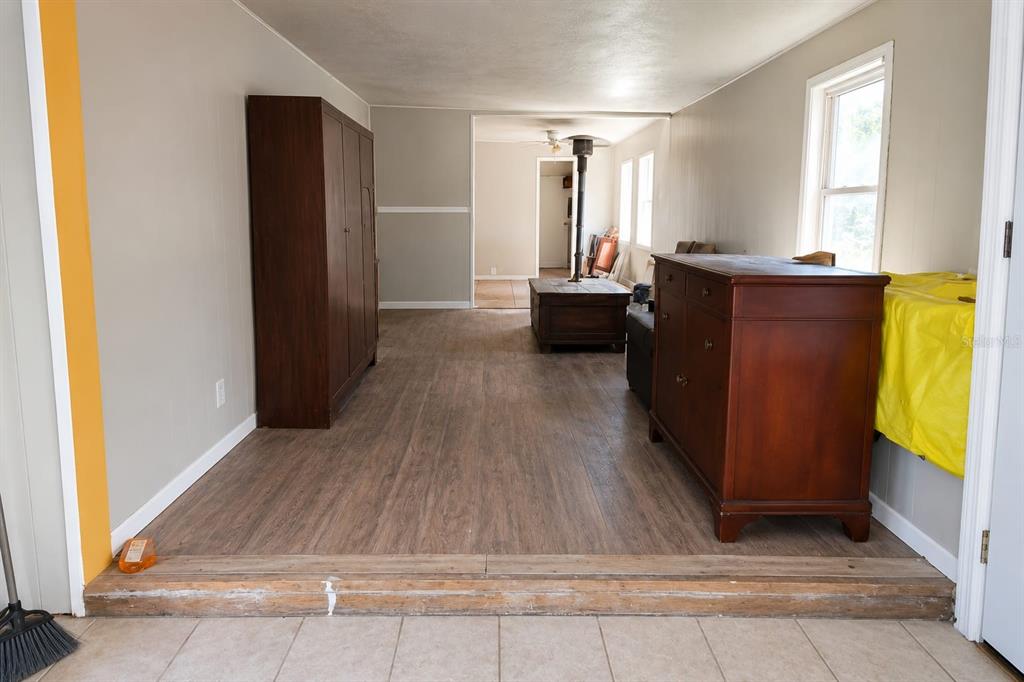 A room with wood-look flooring and a step-up transition from a tiled area — 33620 VERDA AVENUE, LEESBURG, FL