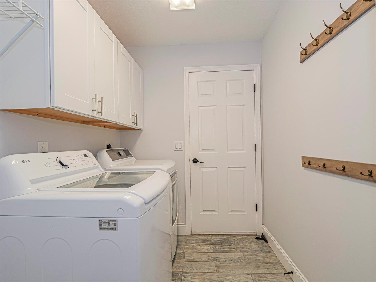 A laundry room features white cabinets, a washer and dryer, and wall-mounted coat hooks — 725 23rd Avenue, Vero Beach FL 32962, VERO BEACH, FL