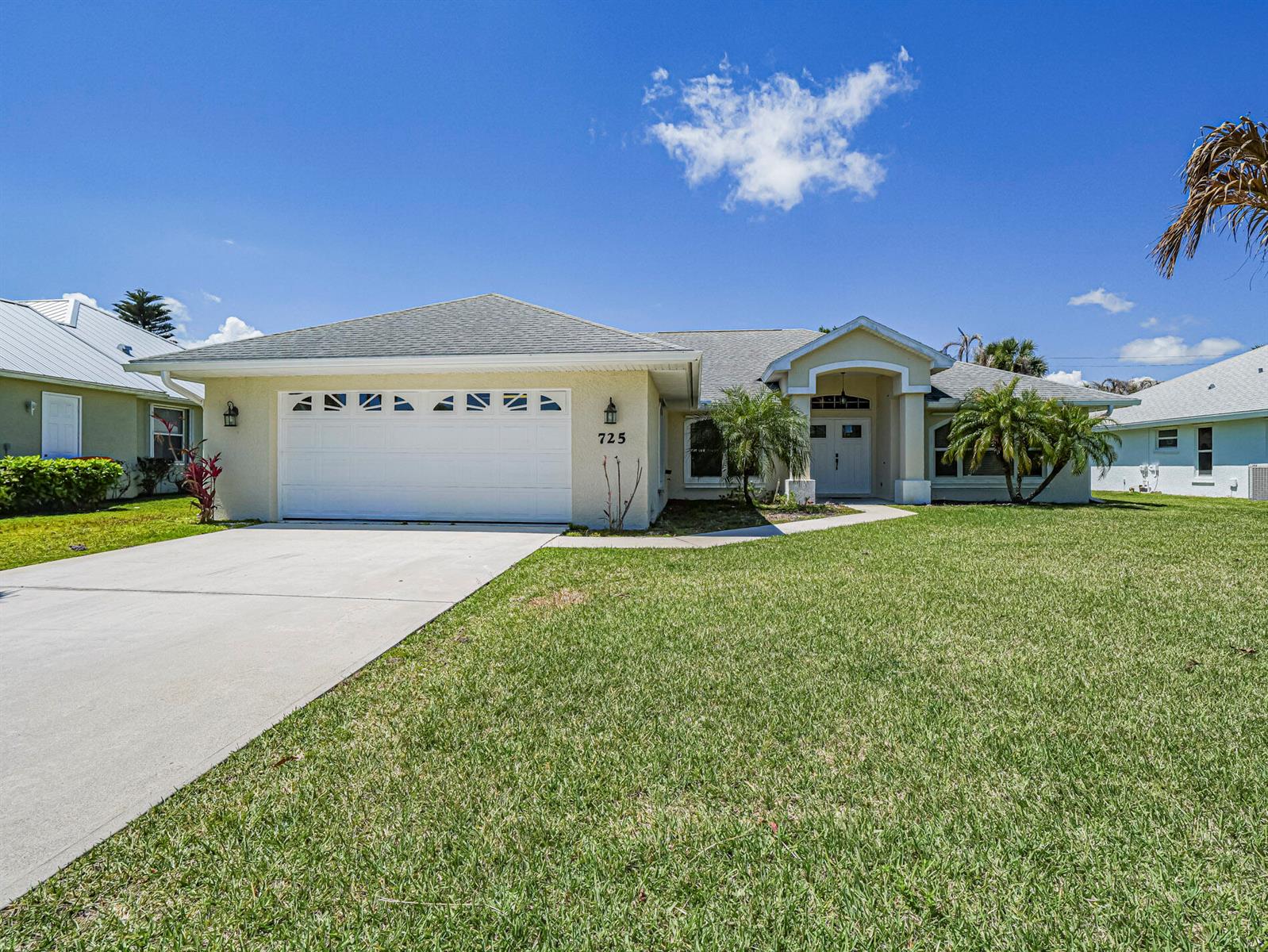 A single-story house with a white garage, beige stucco exterior, and a green lawn — 725 23rd Avenue, Vero Beach FL 32962, VERO BEACH, FL