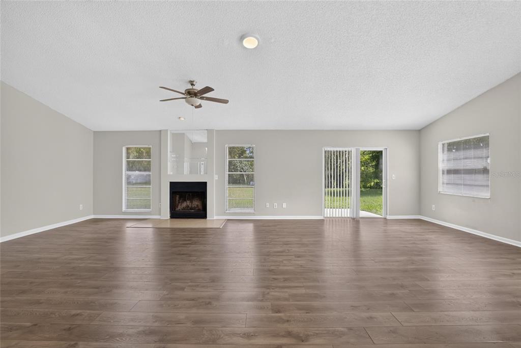 A spacious living room features wood-look flooring, a central fireplace, and a sliding glass door — 1206 SAIL WAY, VALRICO, FL