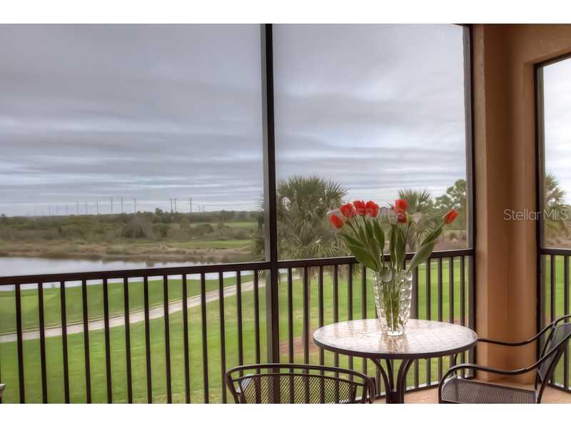 A screened-in balcony overlooks a golf course and a lake under a cloudy sky — 8309 GRAND ESTUARY TRAIL UNIT 206, BRADENTON, FL