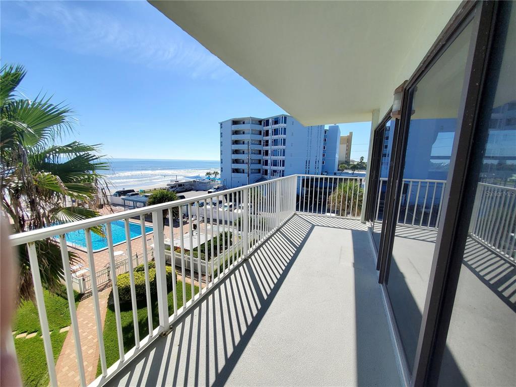 A balcony with a white railing overlooks a swimming pool and the ocean — 1571 S ATLANTIC AVENUE UNIT 405, NEW SMYRNA BEACH, FL