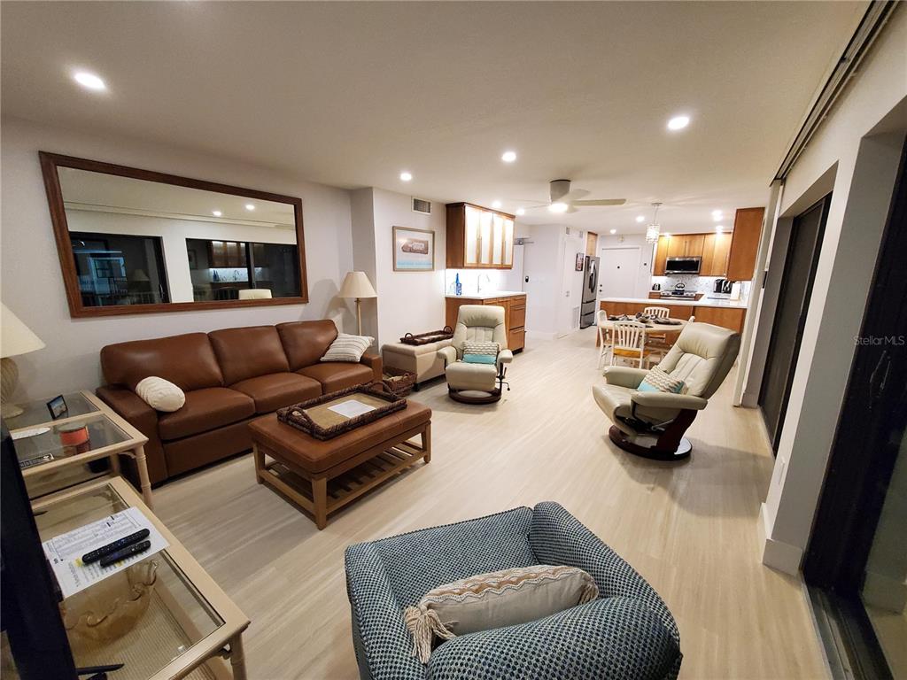A living room with a brown leather sofa, two recliners, and an open-concept kitchen — 1571 S ATLANTIC AVENUE UNIT 405, NEW SMYRNA BEACH, FL