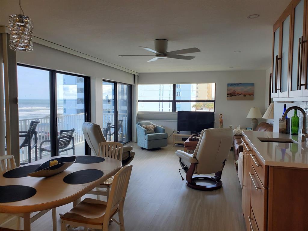 A living and dining area with light wood floors, ocean views, and a kitchen counter — 1571 S ATLANTIC AVENUE UNIT 405, NEW SMYRNA BEACH, FL