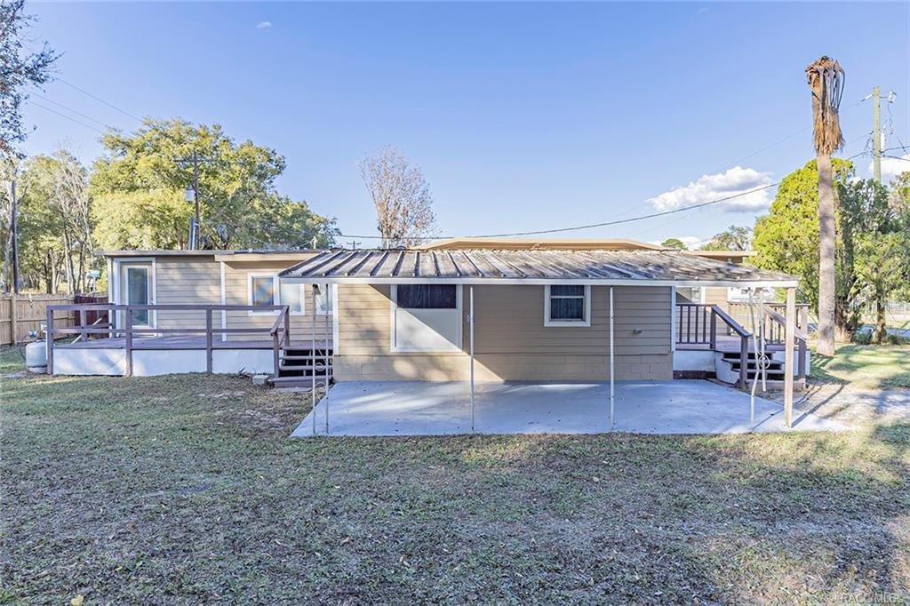 The exterior of a single-story home features a wooden deck and a covered concrete patio — 1672 S CANARY TERRACE, INVERNESS, FL