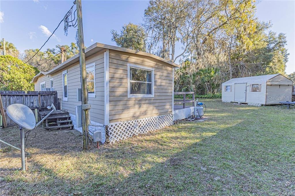 Exterior view of a tan mobile home with a small deck and a detached shed — 1672 S CANARY TERRACE, INVERNESS, FL