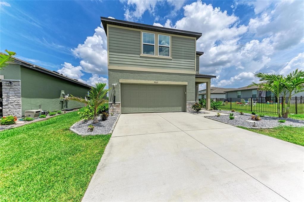 A two-story house with a green exterior, a two-car garage, and a concrete driveway — 9027 WAXWING WAY, PARRISH, FL