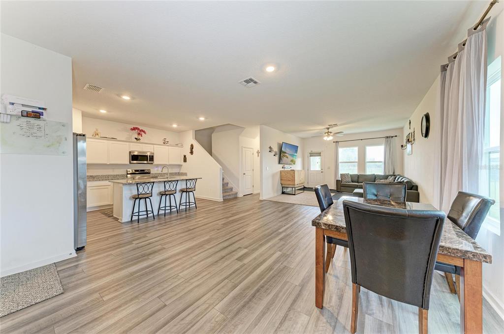 An open-concept living area features a kitchen with an island, dining space, and wood-look flooring — 9027 WAXWING WAY, PARRISH, FL