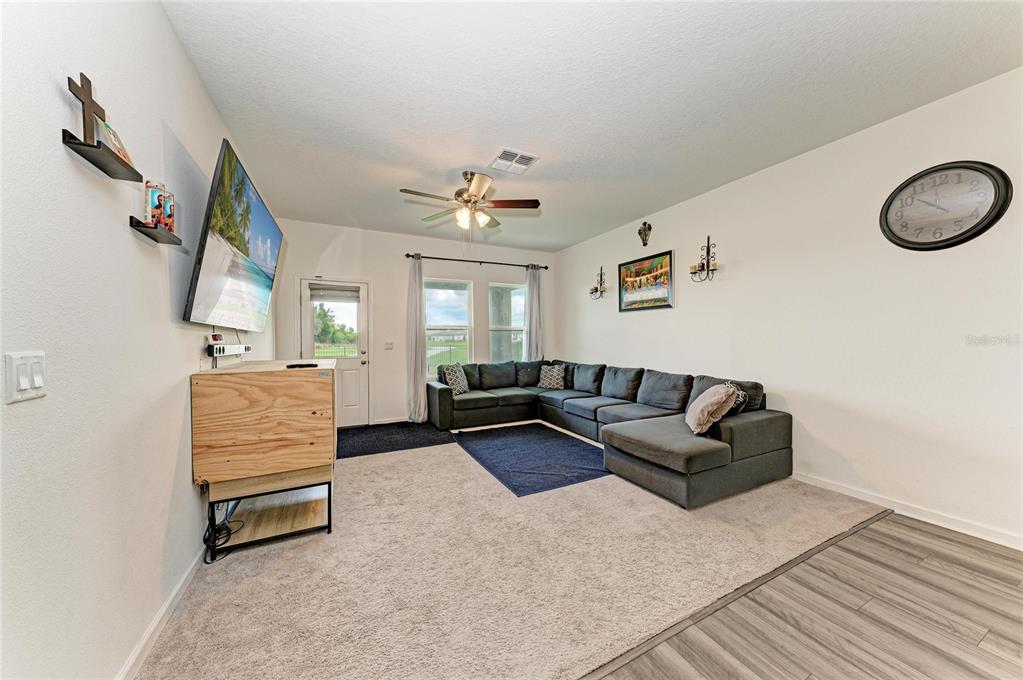 A living room features a large sectional sofa, a wall-mounted television, and a ceiling fan — 9027 WAXWING WAY, PARRISH, FL