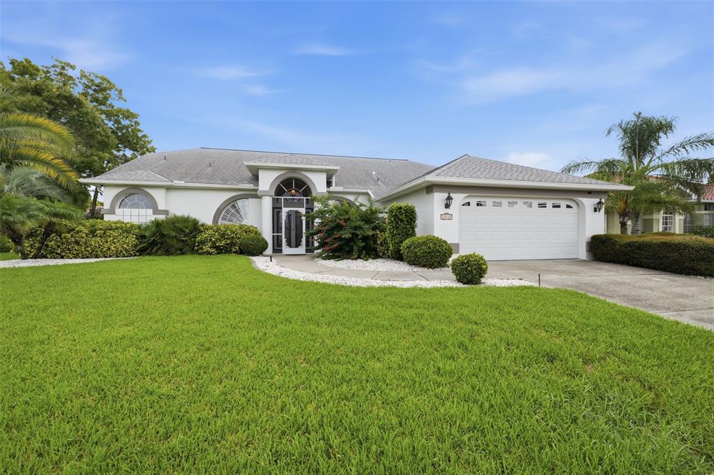 A single-story suburban house with a white stucco exterior, a two-car garage, and landscaped lawn — 13745 WOODWARD DRIVE, HUDSON, FL