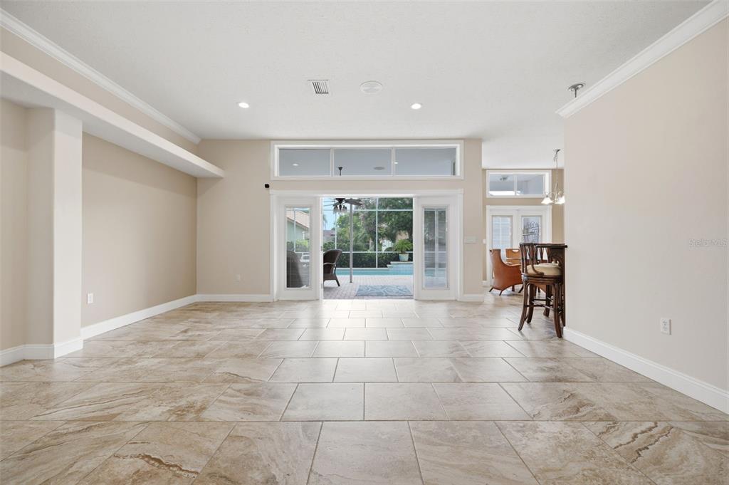 A spacious living area with tile floors, recessed lighting, and sliding glass doors to a pool — 13745 WOODWARD DRIVE, HUDSON, FL