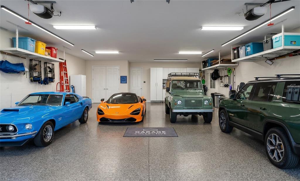 A spacious garage with epoxy flooring houses four parked vehicles and overhead storage shelving — 5845 STORMS AVENUE, THE VILLAGES, FL
