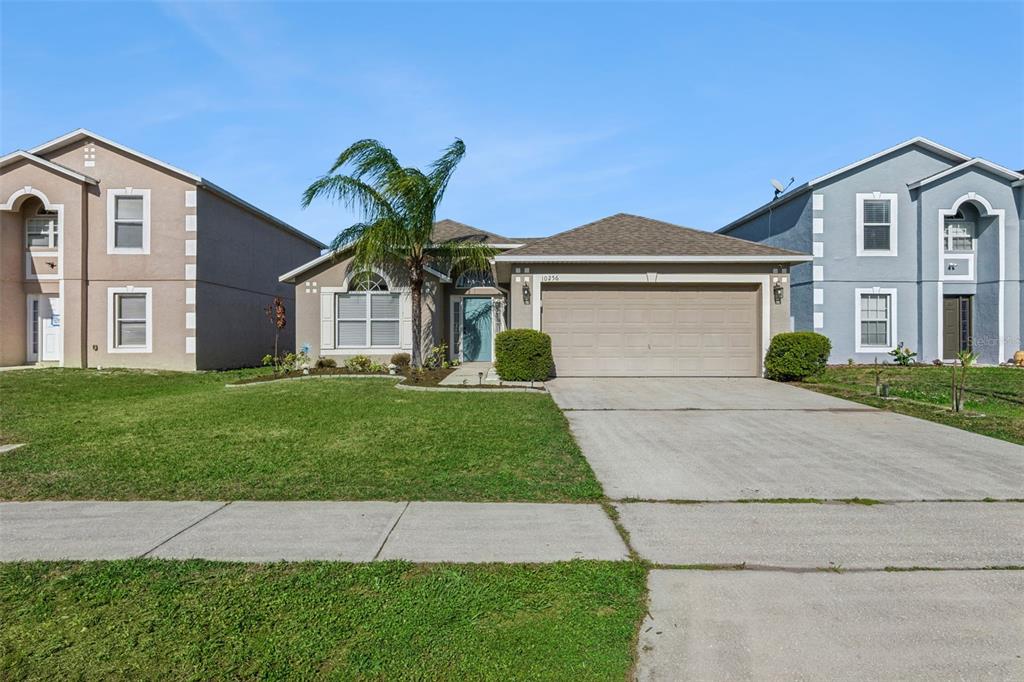 A single-story suburban house with a tan stucco exterior and a two-car garage — 10256 LAXTON STREET, ORLANDO, FL