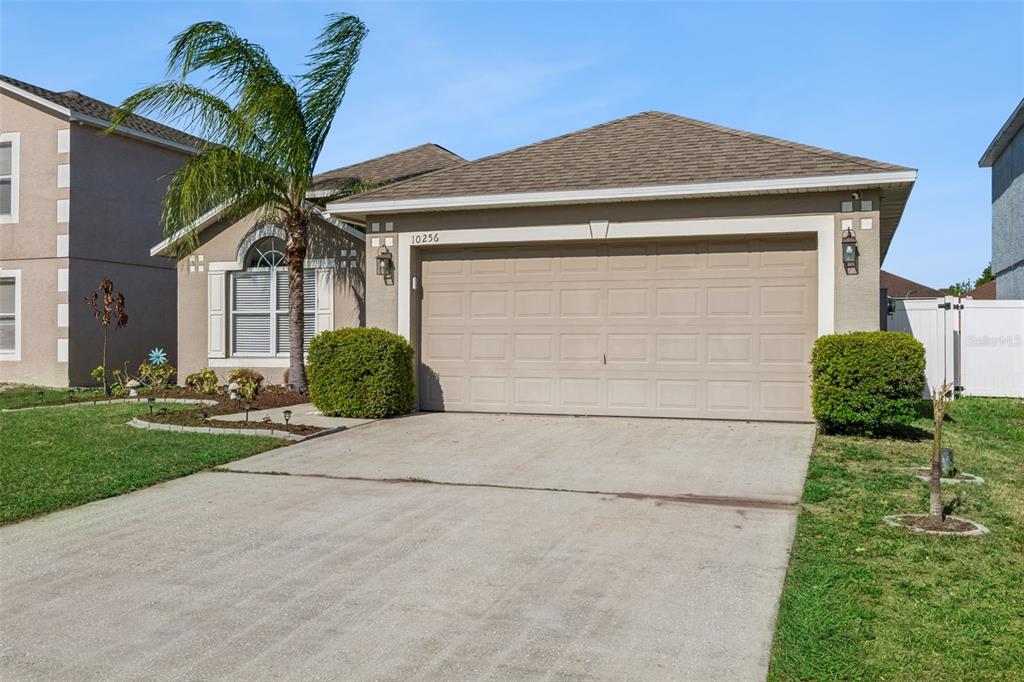 A single-story house with a beige exterior, a two-car garage, and a palm tree — 10256 LAXTON STREET, ORLANDO, FL