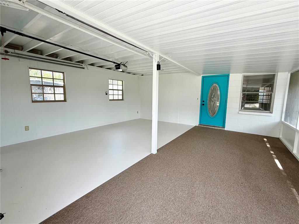 A covered carport area features a turquoise front door, white walls, and a carpeted section — 505 GLAD ROAD, WINTER HAVEN, FL