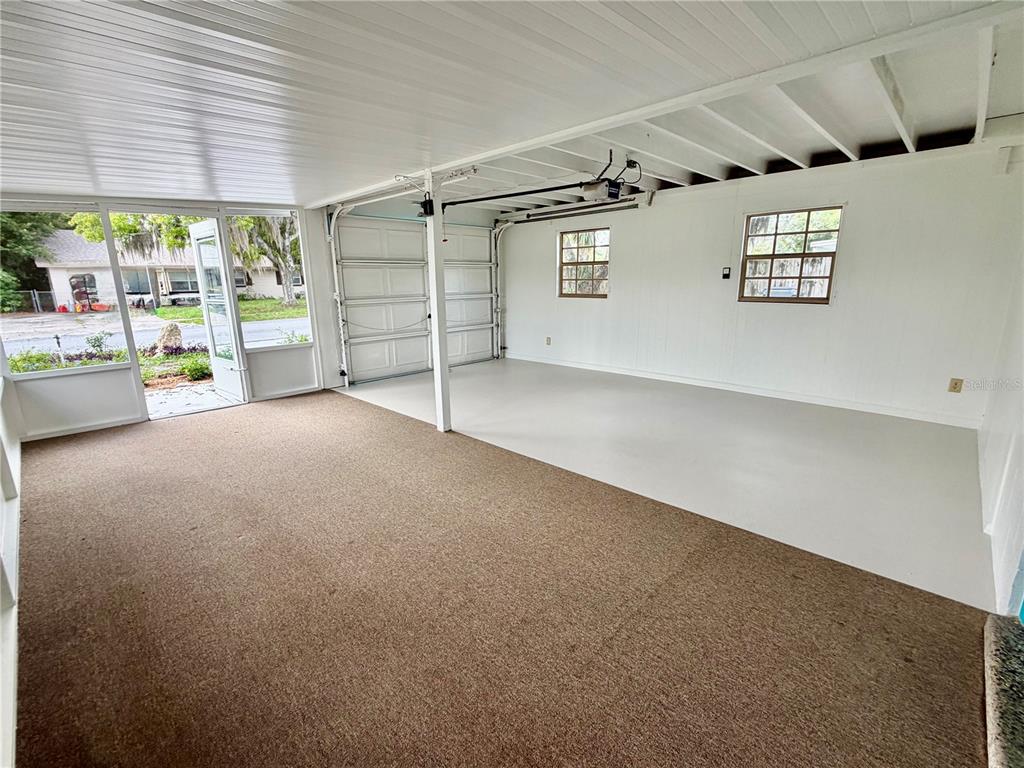 A garage with a carpeted area, a concrete floor, and a screened-in side entrance — 505 GLAD ROAD, WINTER HAVEN, FL