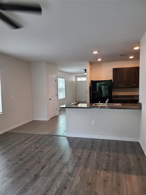 An open-concept kitchen with dark cabinets and a breakfast bar overlooks a living area — 5327 SAN PALERMO DRIVE, BRADENTON, FL