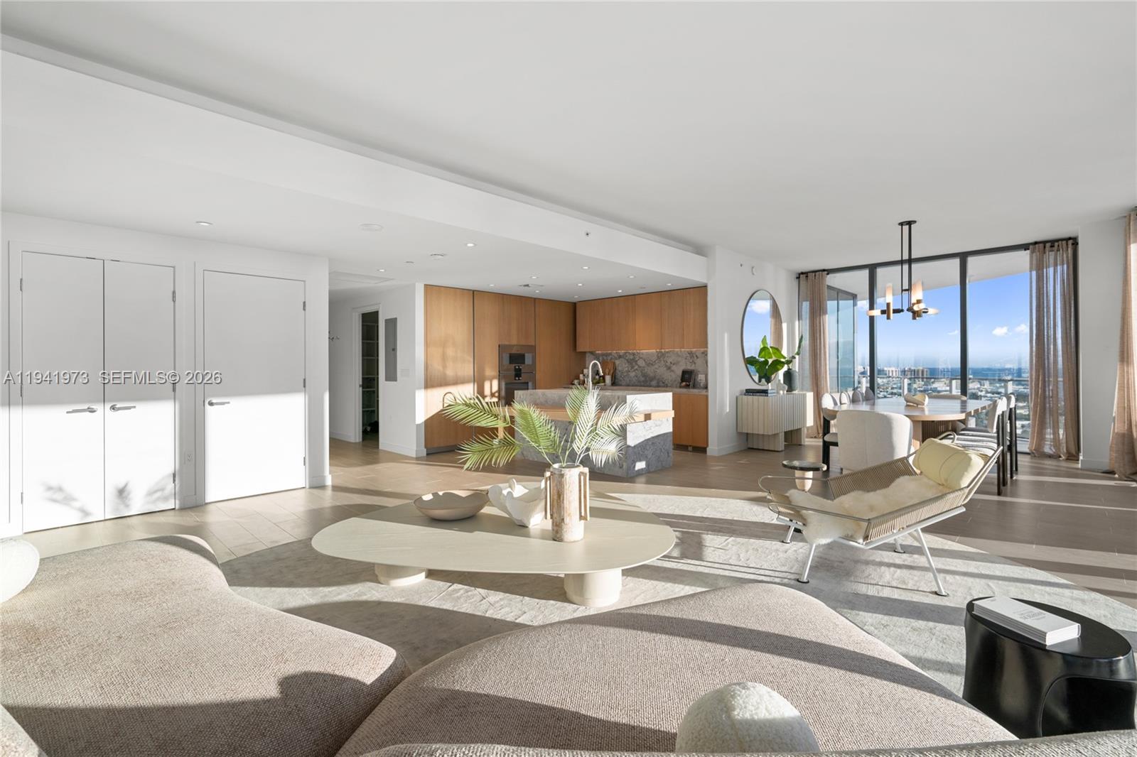 An open-concept living and dining area features light wood floors, modern cabinetry, and floor-to-ceiling windows — 500 Alton Rd, Miami Beach FL 33139, MIAMI BEACH, FL
