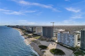 An aerial view of a sandy beach lined with high-rise apartment buildings and a crane — 1012 N Ocean Boulevard # 204, Pompano Beach FL 33062, POMPANO BEACH, FL