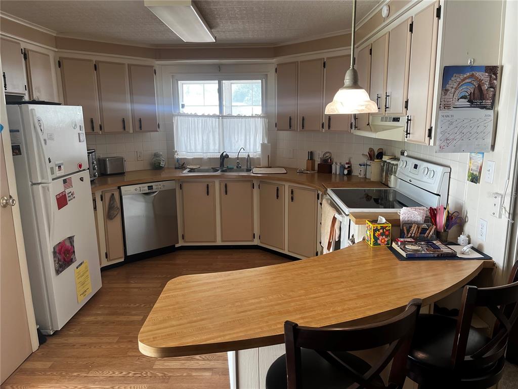 A kitchen features light-colored cabinets, a peninsula with bar seating, and wood-look flooring — 192 PHILADELPHIA BOULEVARD UNIT 9, PALM HARBOR, FL