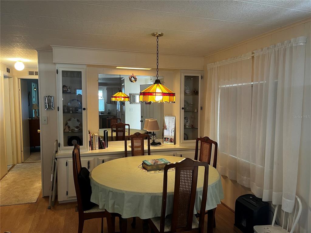 A dining room features a round table, chairs, a stained-glass pendant light, and built-in cabinetry — 192 PHILADELPHIA BOULEVARD UNIT 9, PALM HARBOR, FL