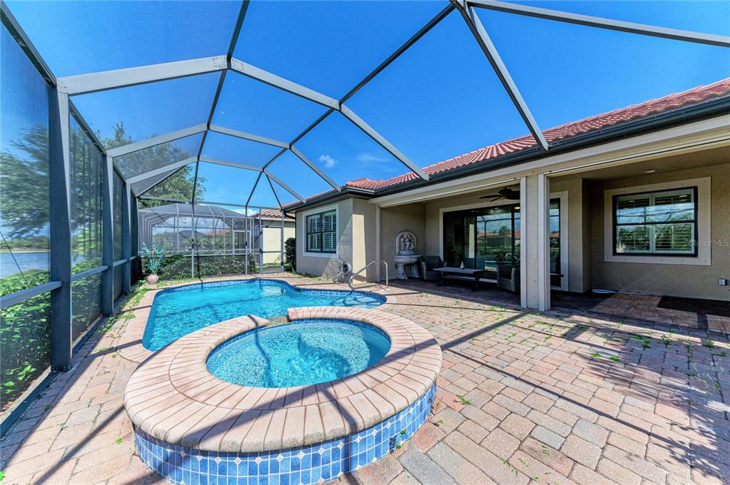 A screened-in patio features a swimming pool, a raised hot tub, and paver flooring — 1310 CIELO COURT, NORTH VENICE, FL