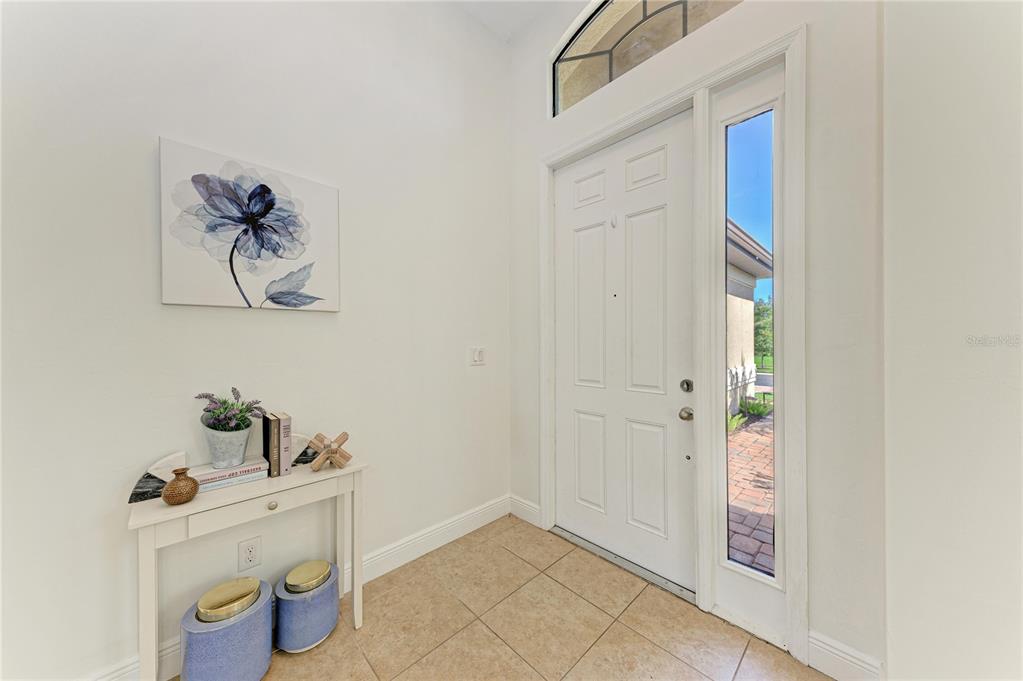 A bright entryway features a white front door, tile flooring, and a small console table — 1310 CIELO COURT, NORTH VENICE, FL