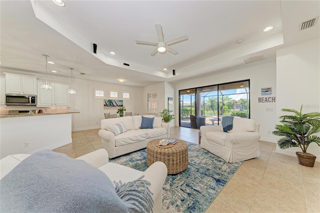 A bright living room features white furniture, a patterned blue rug, and sliding glass doors — 1310 CIELO COURT, NORTH VENICE, FL