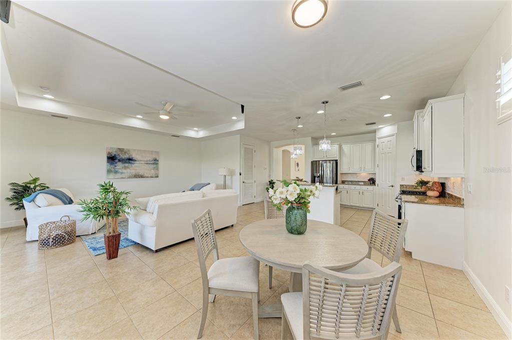 An open-concept living and dining area features white cabinetry, tile flooring, and neutral furniture — 1310 CIELO COURT, NORTH VENICE, FL