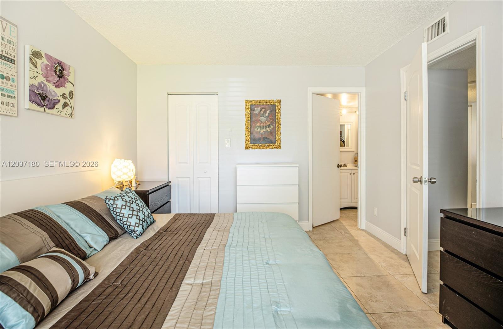 A bedroom features a bed with blue and brown bedding, a dresser, and an attached bathroom — 15780 SW 106th Ter # 107, Miami FL 33196, MIAMI, FL