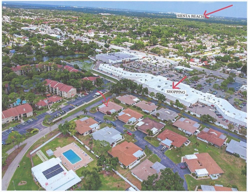 An aerial view shows a residential community with a swimming pool near a shopping center — 3501 N VILLAGE COURT UNIT 220, SARASOTA, FL