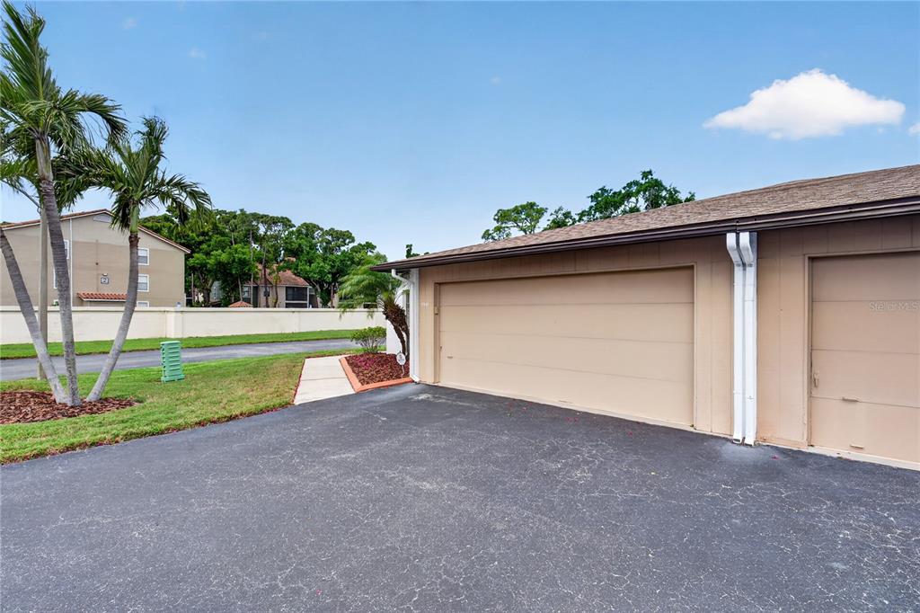 A tan building exterior features two closed garage doors and a paved driveway — 3501 N VILLAGE COURT UNIT 220, SARASOTA, FL