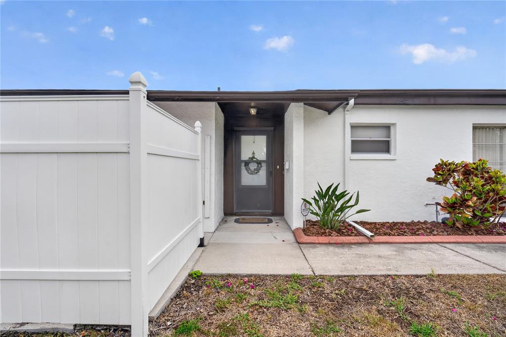 The exterior of a white house features a front door, a walkway, and a fence — 3501 N VILLAGE COURT UNIT 220, SARASOTA, FL