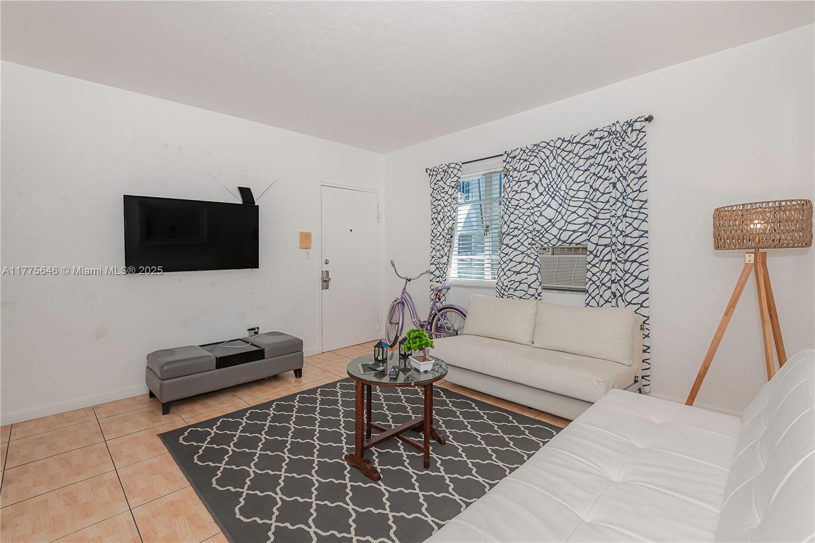 A living room features white walls, tiled floors, two white sofas, and a patterned rug — 655 83rd St # 55, Miami Beach FL 33141, MIAMI BEACH, FL