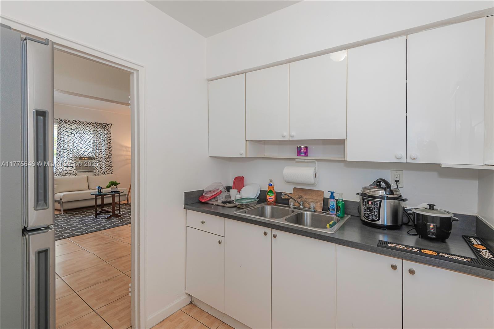 A small kitchen features white cabinets, a double sink, and a gray countertop — 655 83rd St # 55, Miami Beach FL 33141, MIAMI BEACH, FL