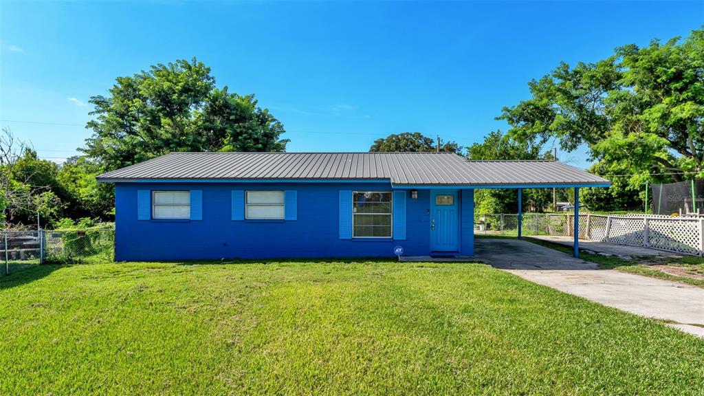 A blue single-story house with a metal roof and an attached carport sits on grass — 707 N LORRI AVENUE, LAKELAND, FL