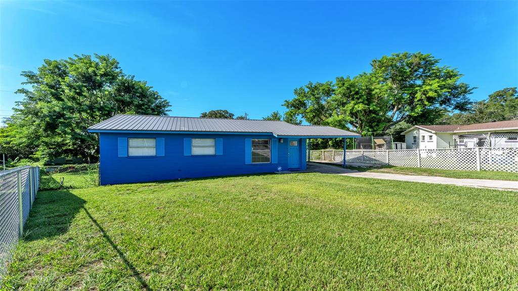 A blue single-story house with a metal roof stands on a grassy lot — 707 N LORRI AVENUE, LAKELAND, FL