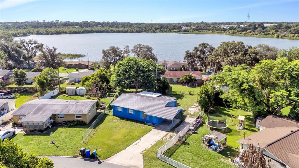 An aerial view shows a blue house with a metal roof near a large lake — 707 N LORRI AVENUE, LAKELAND, FL
