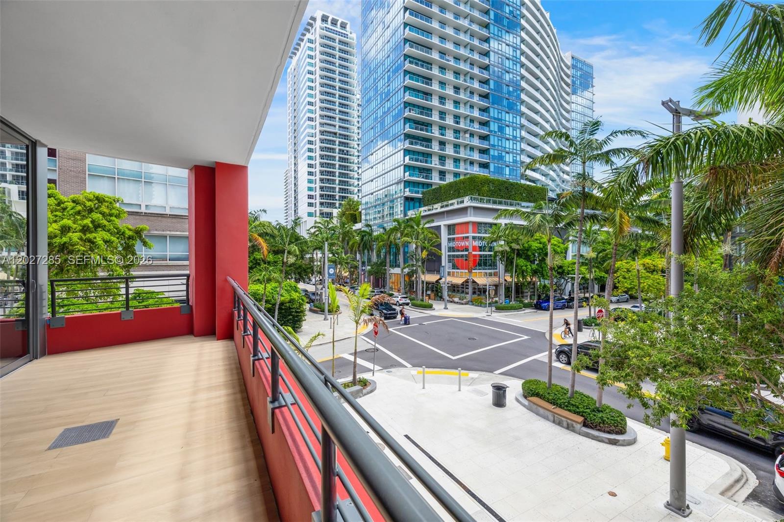 A balcony with red walls and metal railings overlooks a city intersection with high-rise buildings — 90 NE 32nd St # 212, Miami FL 33127, MIAMI, FL