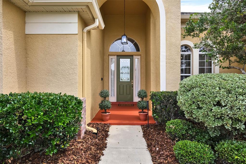 A concrete walkway leads to the front entrance of a house with a green door — 1527 GANTS CIRCLE, KISSIMMEE, FL