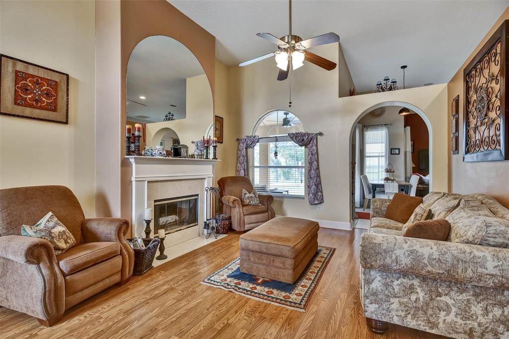 A living room features a fireplace, arched mirror, ceiling fan, and hardwood flooring — 1527 GANTS CIRCLE, KISSIMMEE, FL