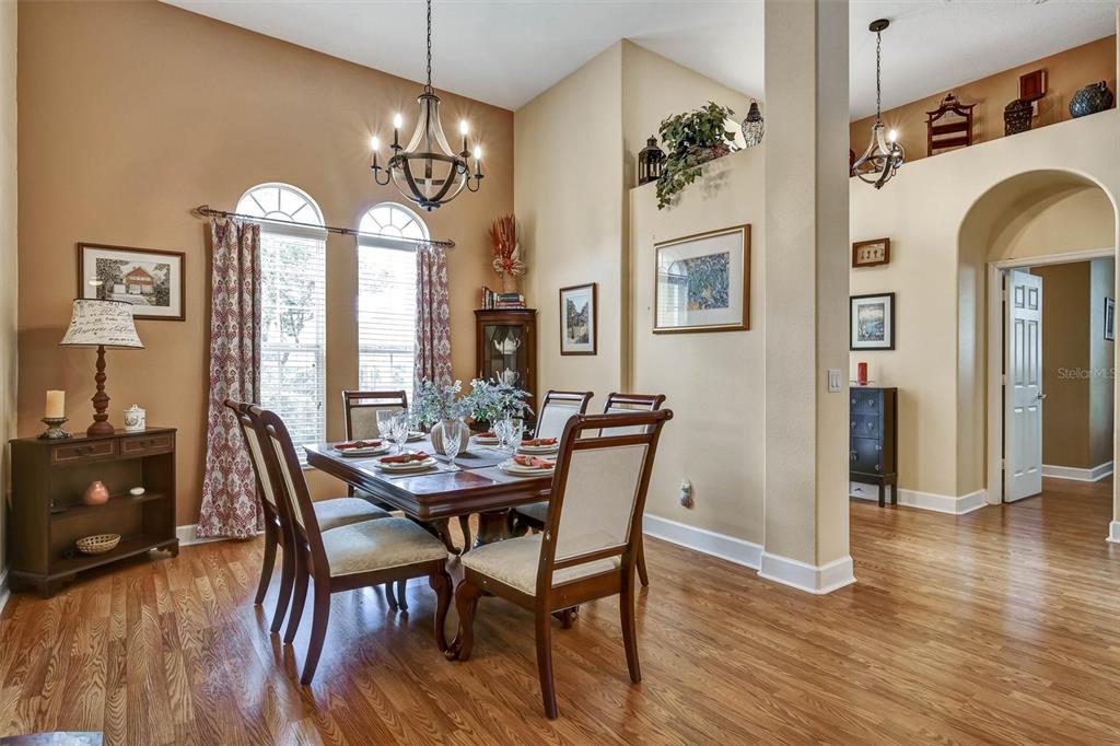 A dining room with hardwood floors, a wooden table, and a chandelier under high ceilings — 1527 GANTS CIRCLE, KISSIMMEE, FL