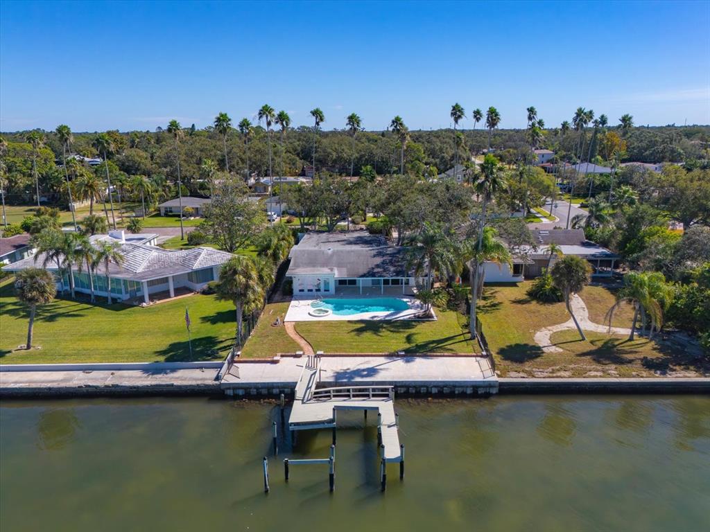 An aerial view shows a waterfront house with a swimming pool and a private dock — 1614 SANTA BARBARA DRIVE, DUNEDIN, FL