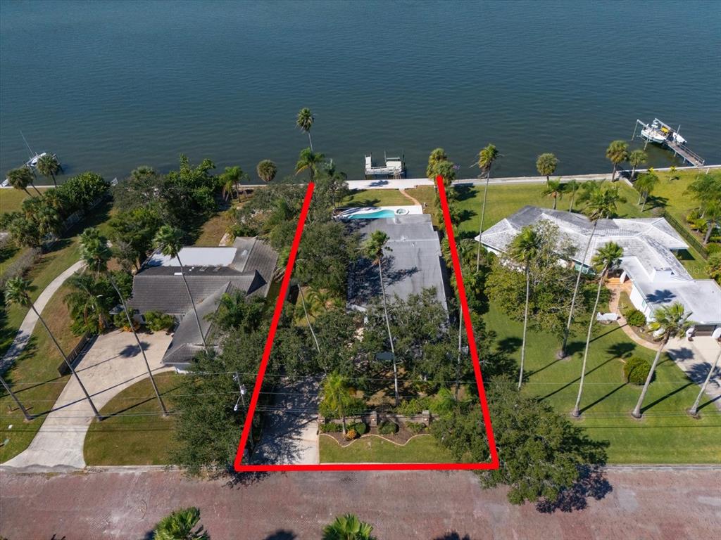An aerial view shows a waterfront house with a pool and dock on a lot — 1614 SANTA BARBARA DRIVE, DUNEDIN, FL