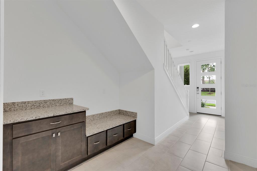 An entryway features a built-in storage bench and cabinet with granite countertops and tile flooring — 9868 BUCKLOW HILL DRIVE, ORLANDO, FL