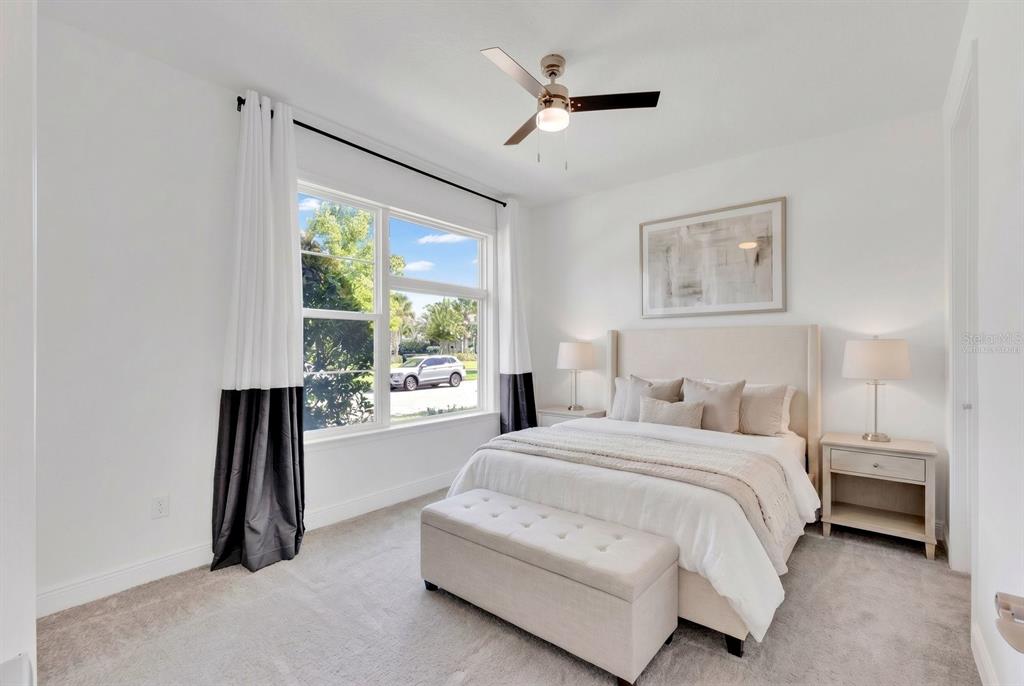 A bright bedroom features a queen bed, a tufted bench, and a large window — 9868 BUCKLOW HILL DRIVE, ORLANDO, FL