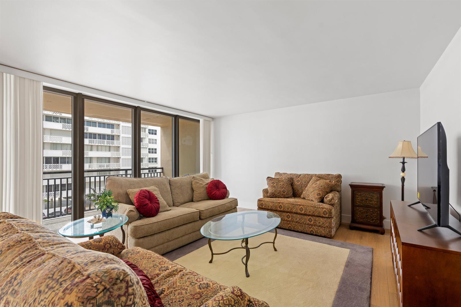 A living room features a beige sofa, a patterned loveseat, glass tables, and a balcony view — 1180 S Ocean # 0044, Boca Raton FL 33432, BOCA RATON, FL