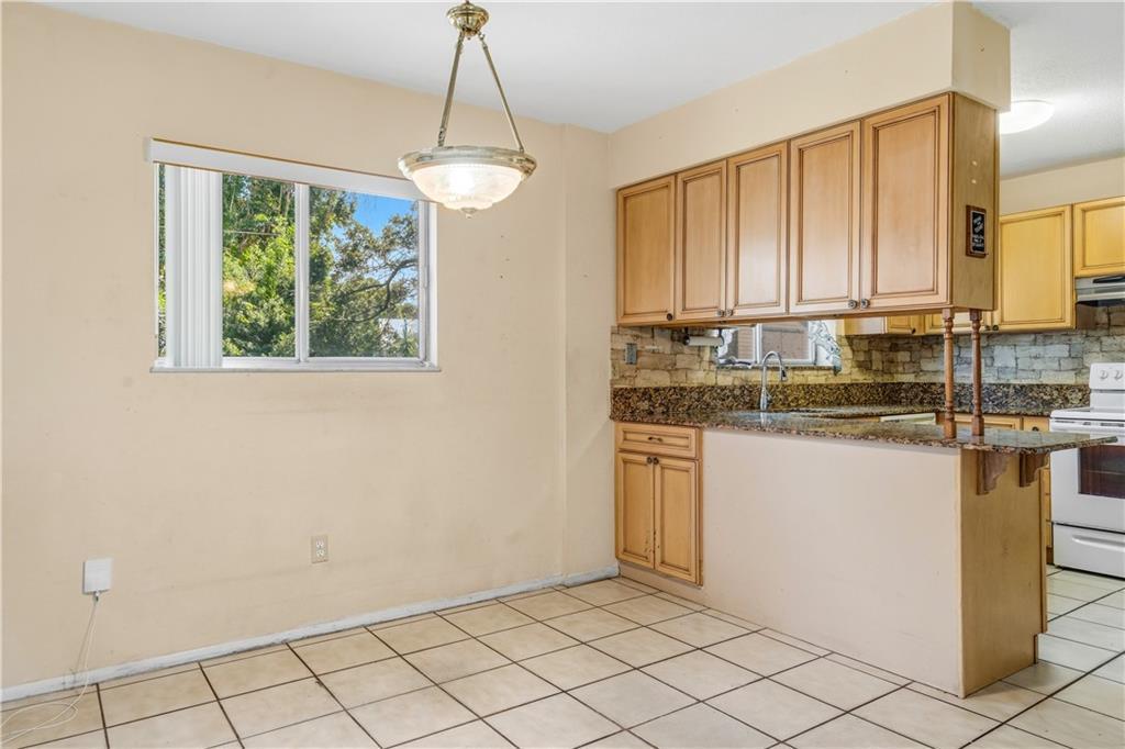 A kitchen and dining area with light-colored walls, tile flooring, and wood cabinetry — VERO BEACH, FL