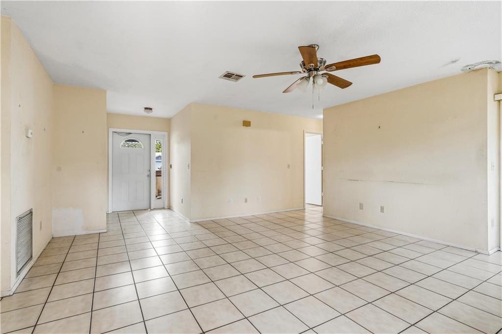An empty room with beige tile flooring, light-colored walls, and a ceiling fan — VERO BEACH, FL