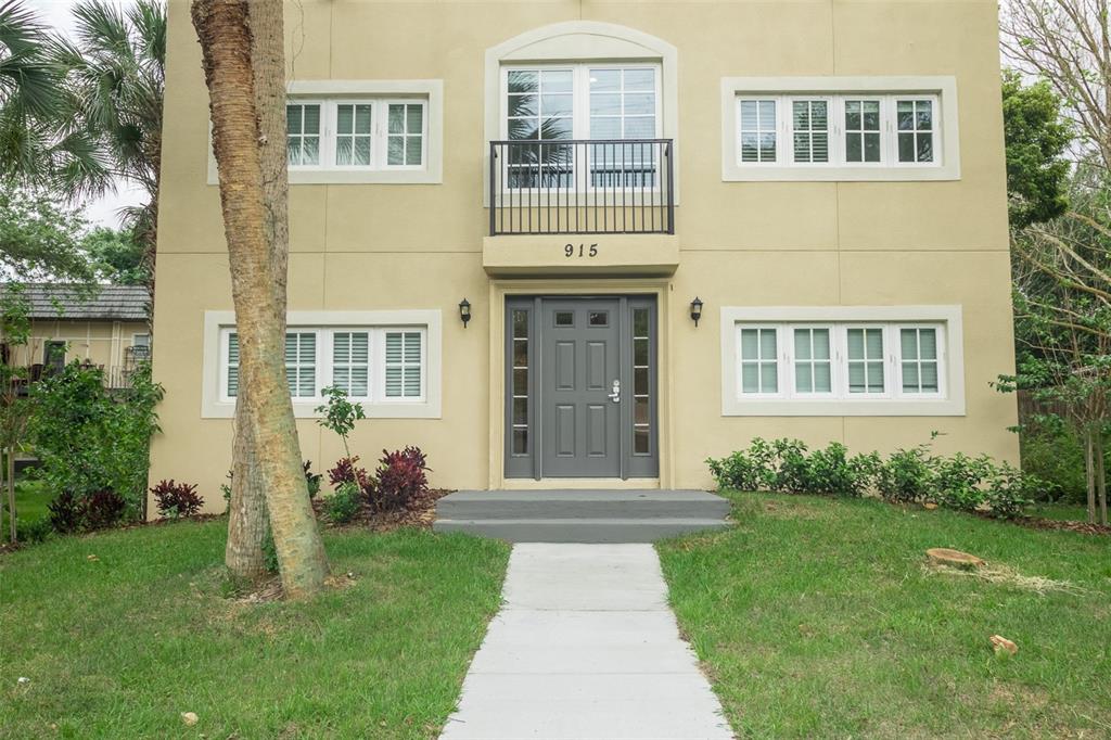 A two-story tan building features a gray front door, a small balcony, and white-trimmed windows — 915 E PALMETTO STREET, LAKELAND, FL